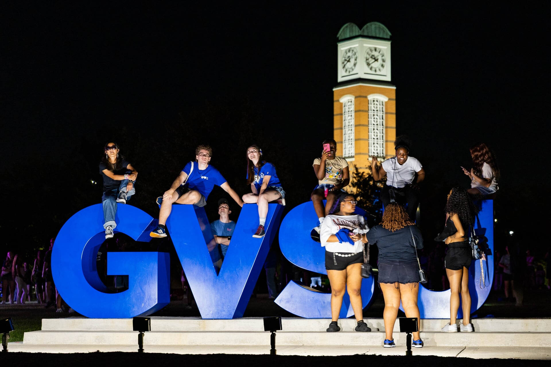 students sit on the big GVSU letters on the Valley campus to watch the Laker Kickoff Drone Show